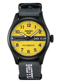 A Seiko Honda Automatic watch with a bright yellow dial, black case, and a dark gray woven fabric strap featuring white and red Seiko branding.