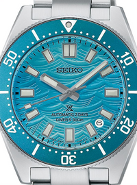 A close-up of a Seiko dive watch with a silver stainless steel case and bracelet, featuring a vibrant turquoise blue dial with a wavy pattern and a matching blue bezel.