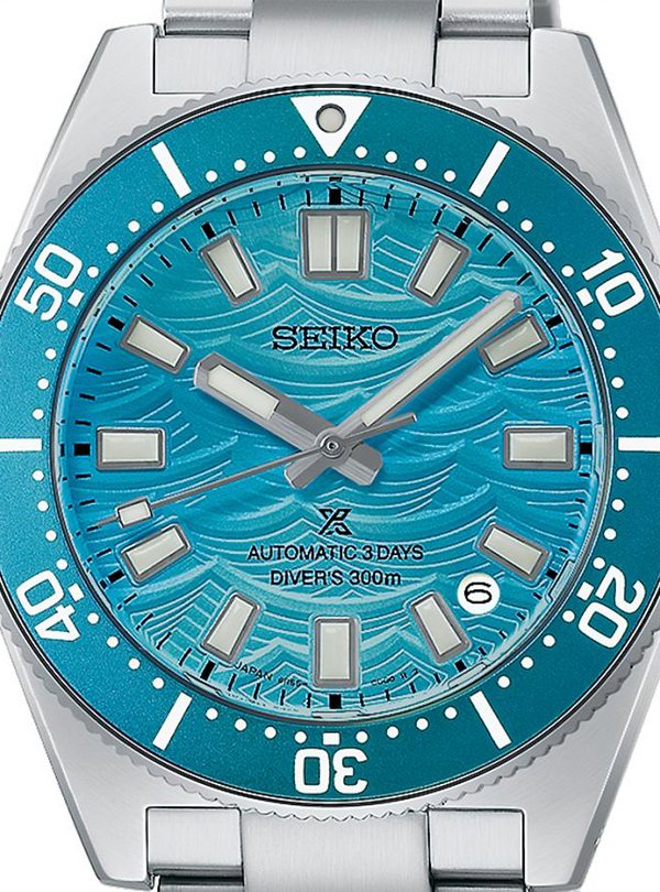 A close-up of a Seiko dive watch with a silver stainless steel case and bracelet, featuring a vibrant turquoise blue dial with a wavy pattern and a matching blue bezel.