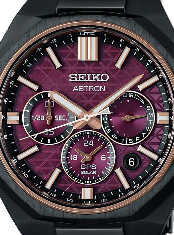 Close-up of a Seiko Astron watch with a black case, black bezel, and a textured magenta-purple dial with rose gold-tone markers and hands.