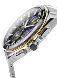 Close-up of a stainless steel chronograph watch with a dark blue dial, gold-tone bezel accents, and a silver metal bracelet on a white background.