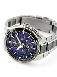 A Seiko Astronom chronograph watch with a silver titanium case and link bracelet, featuring a deep blue sunburst dial with gold-tone accents and subdials.