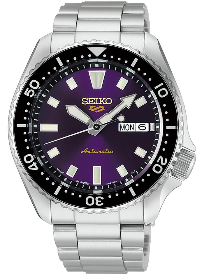A Seiko stainless steel wristwatch with a purple dial, black bezel, and silver link bracelet, shown against a plain white background.