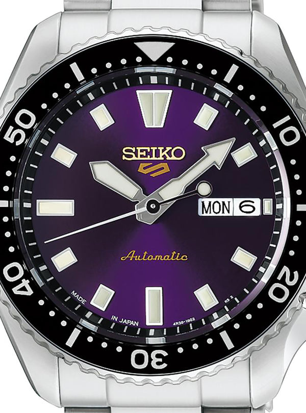A Seiko automatic watch with a silver stainless steel case and bracelet, featuring a prominent purple dial, black rotating bezel, and silver hour markers.