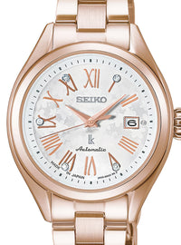 A Seiko women's automatic watch featuring a rose gold-tone metal bracelet and case, a white dial with rose gold Roman numerals and hands, and crystal hour markers.