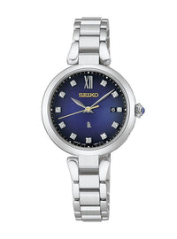 A Seiko women's watch featuring a polished silver titanium link bracelet, a round silver case, and a deep blue dial with gold-tone hands and Roman numeral XII.